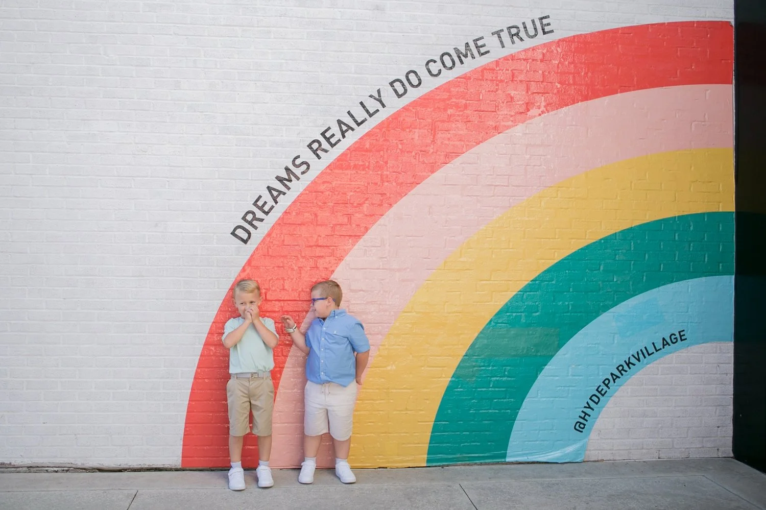 Twin boys standing in front of the Dreams Really Do Come True rainbow mural at Hyde Park Village Tampa
