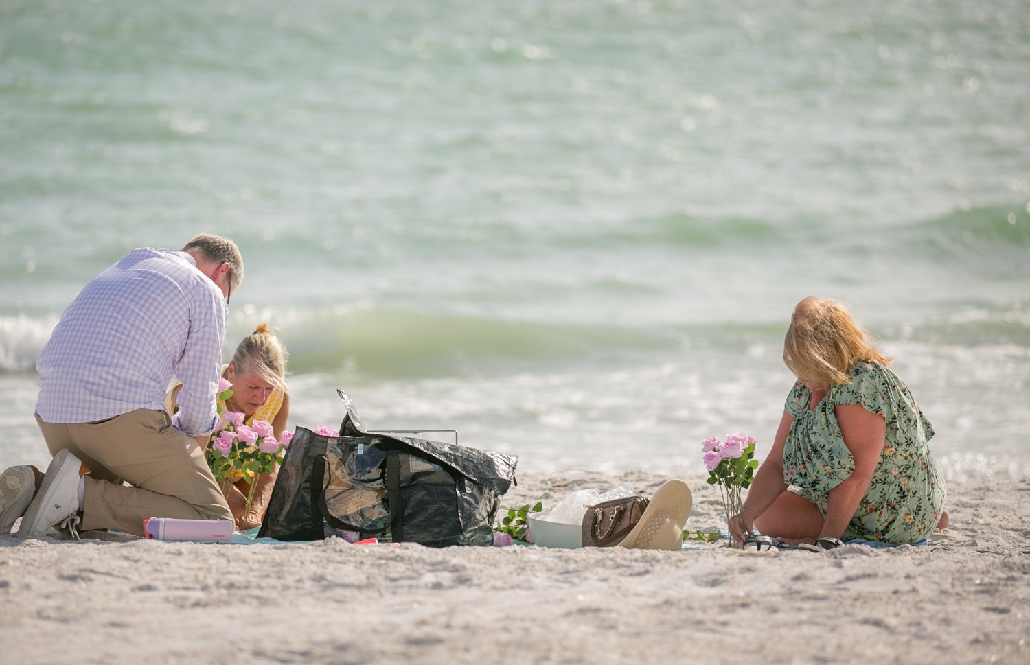 Family setting up a pink rose floral arch in the sand before a surprise proposal at Upham Beach, St. Pete Beach