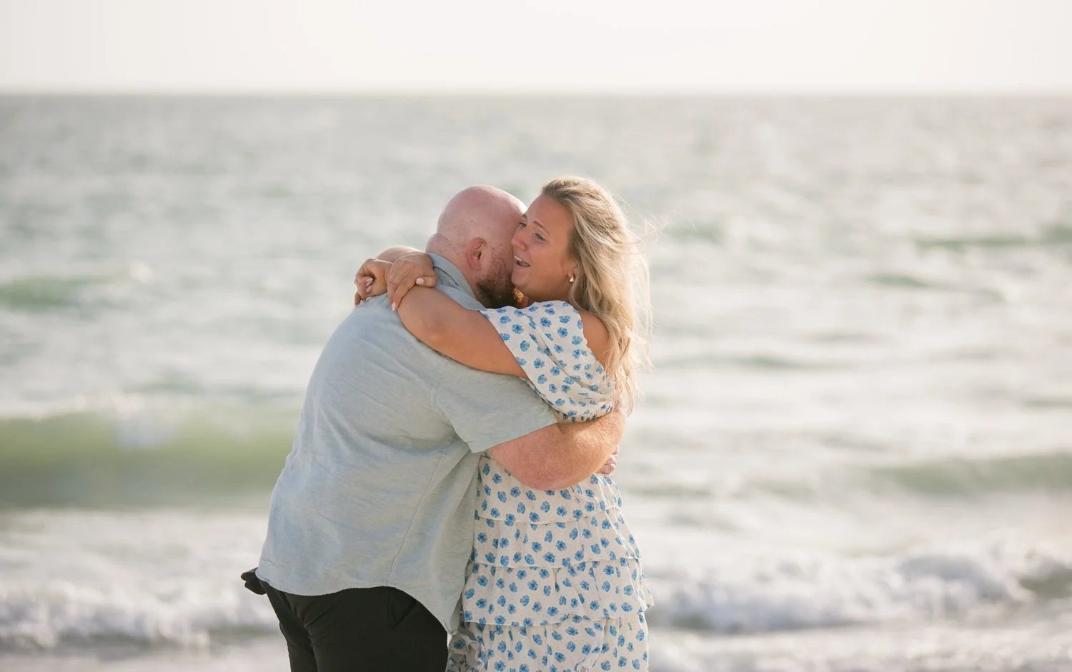 Engaged couple embracing on the beach after a surprise proposal at Upham Beach
