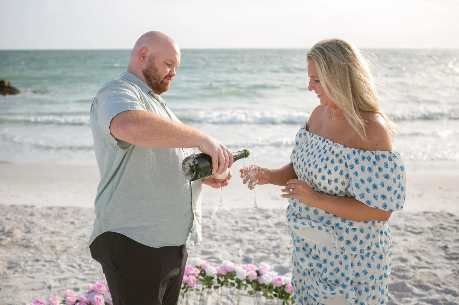 Couple pouring Argyle Oregon sparkling wine to celebrate their engagement at Upham Beach