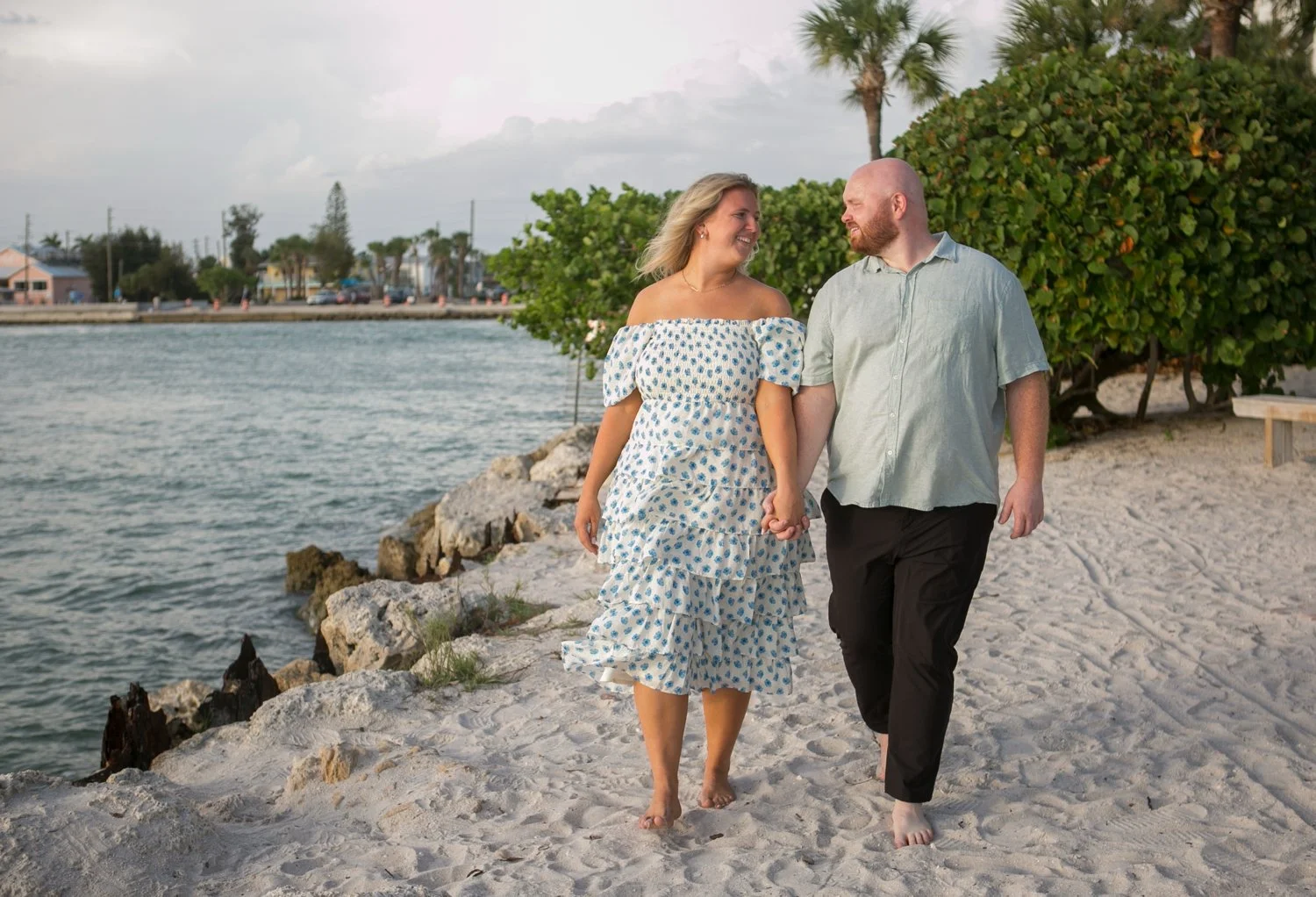 Engaged couple holding hands and walking along the shoreline at Upham Beach