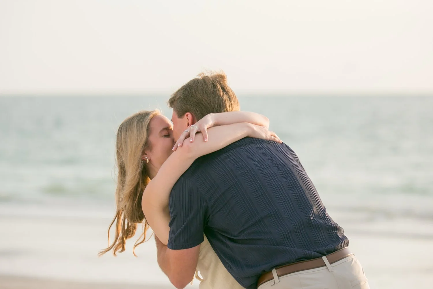 Bride-to-be hugging her fiancé after saying yes on the beach