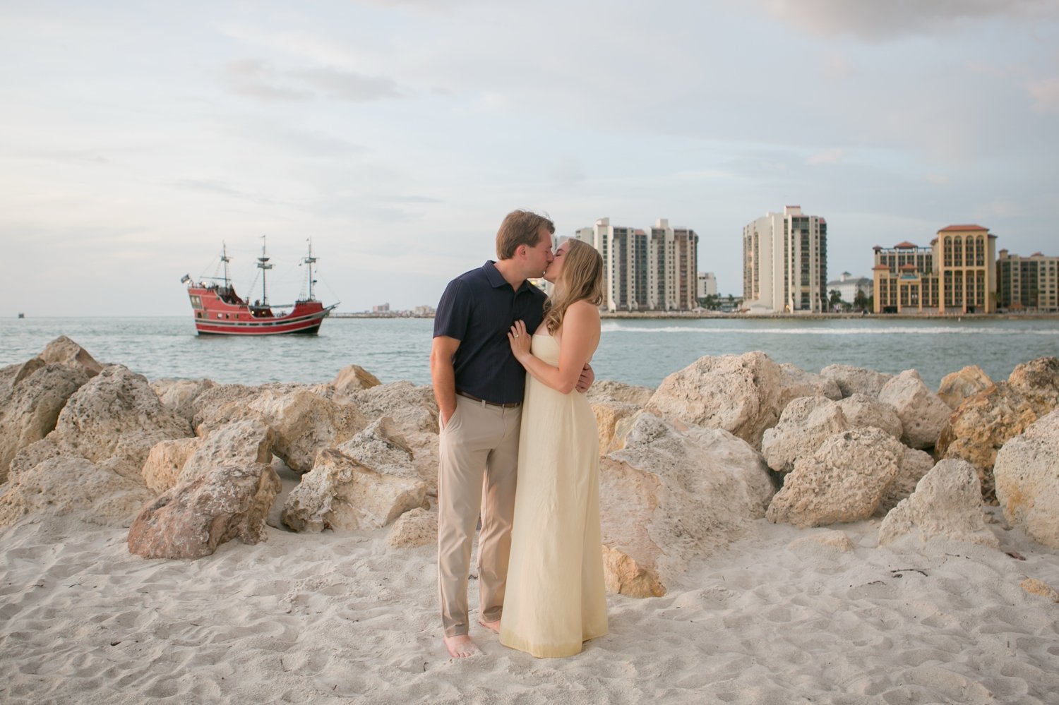 Couple kissing near the rock jetty with pirate ship cruise in background