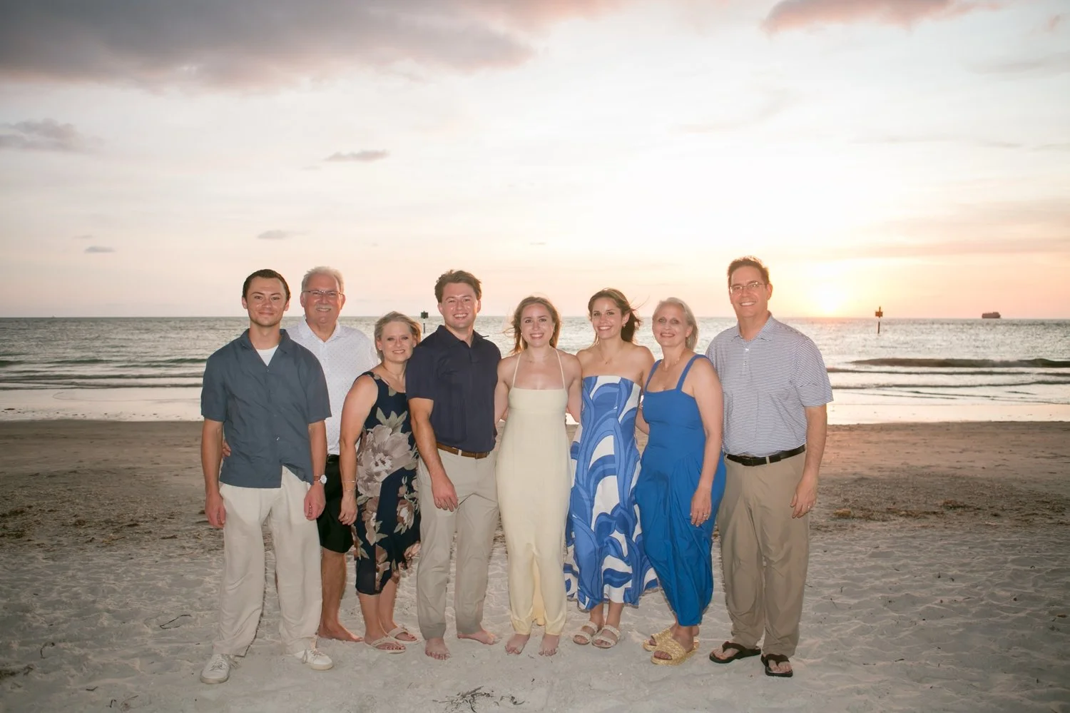 Both families posing together on the beach at sunset