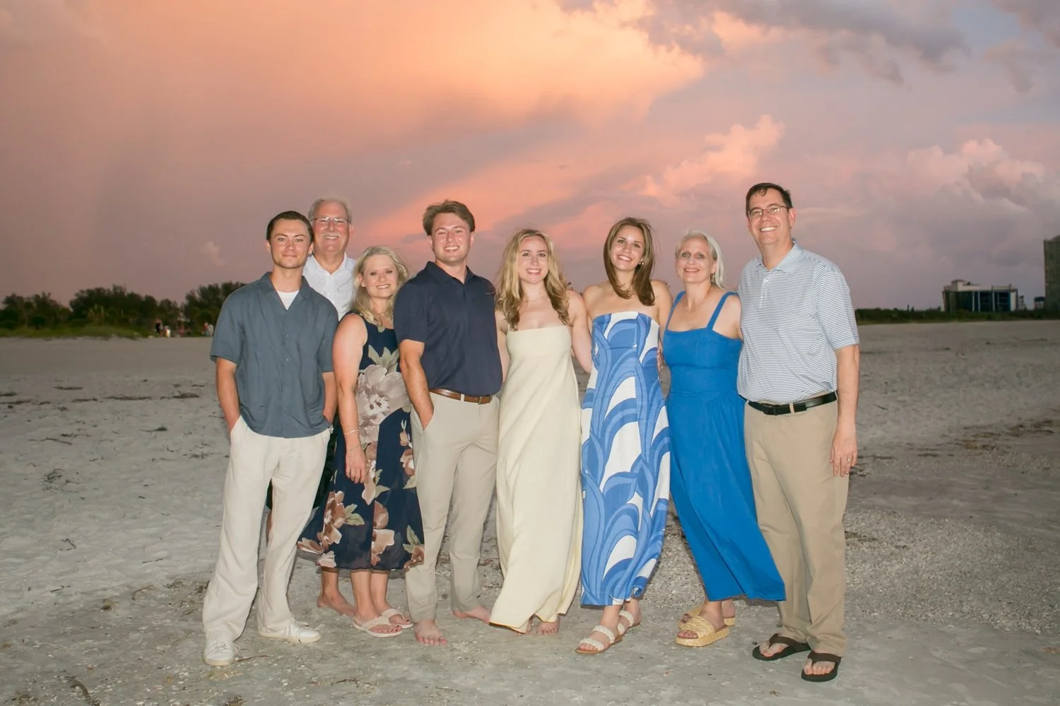 Both families posing together on the beach at sunset