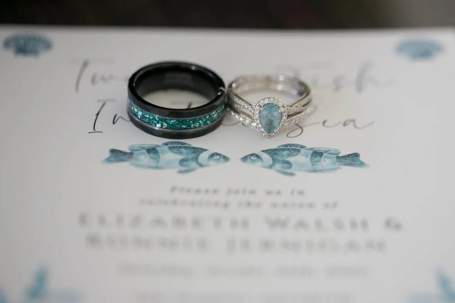 Wedding bands resting on the ocean-themed wedding invitation