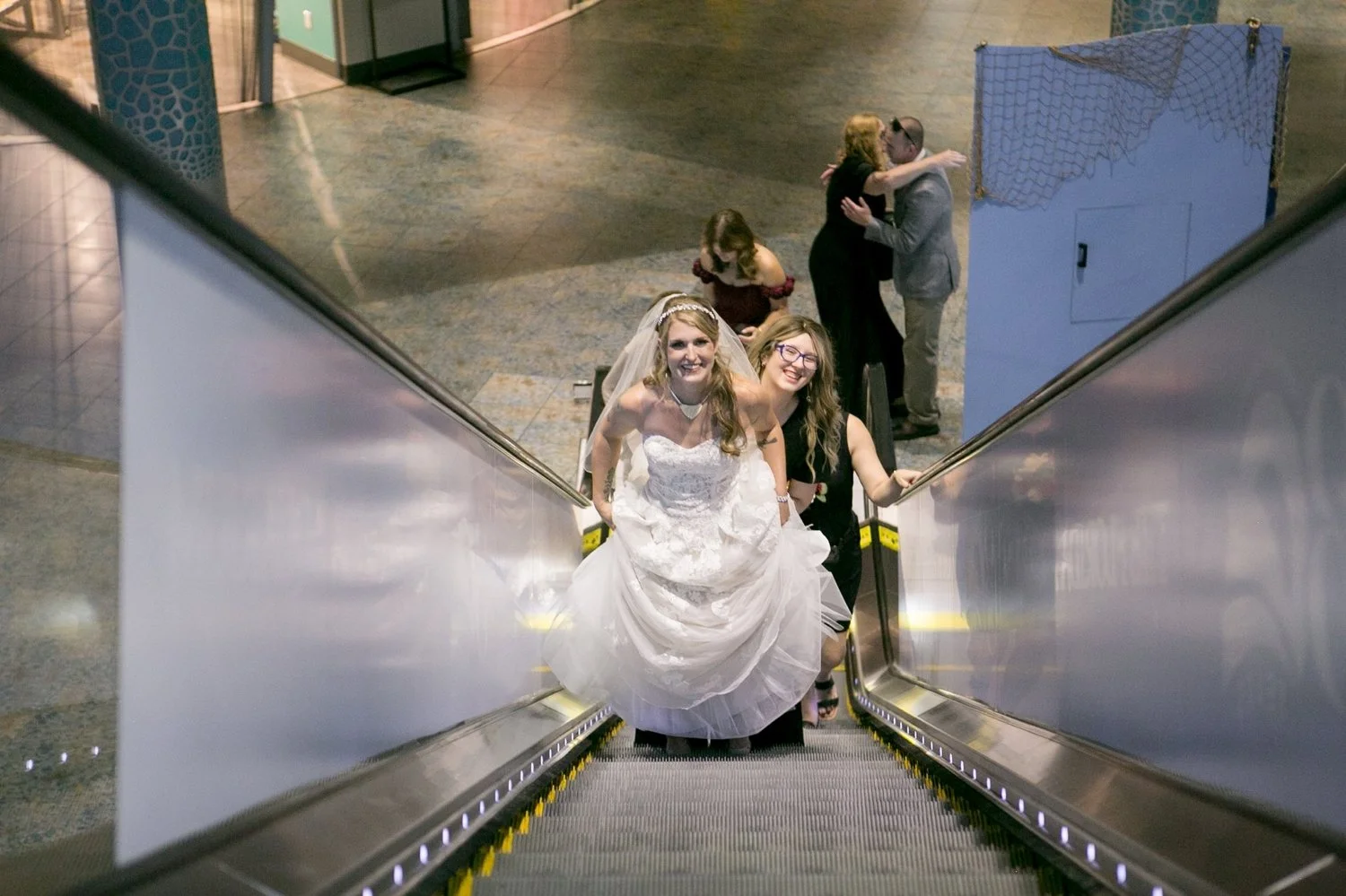 Bride riding the escalator down with her bridesmaids at The Florida Aquarium
