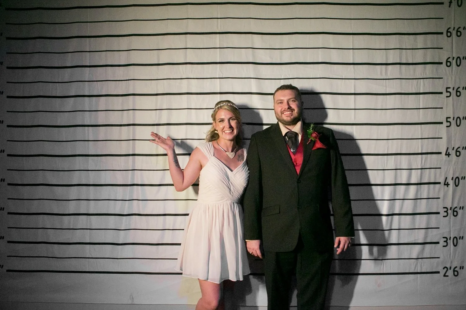 Bride and groom posing in front of a mugshot height chart on the American Victory Ship