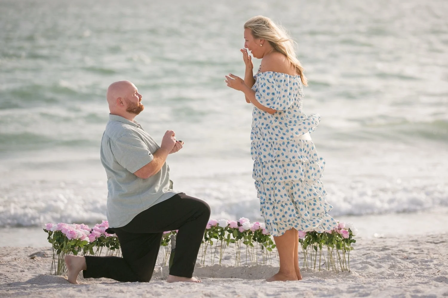 Man on one knee proposing during a surprise beach proposal at Upham Beach, St. Pete Beach Florida