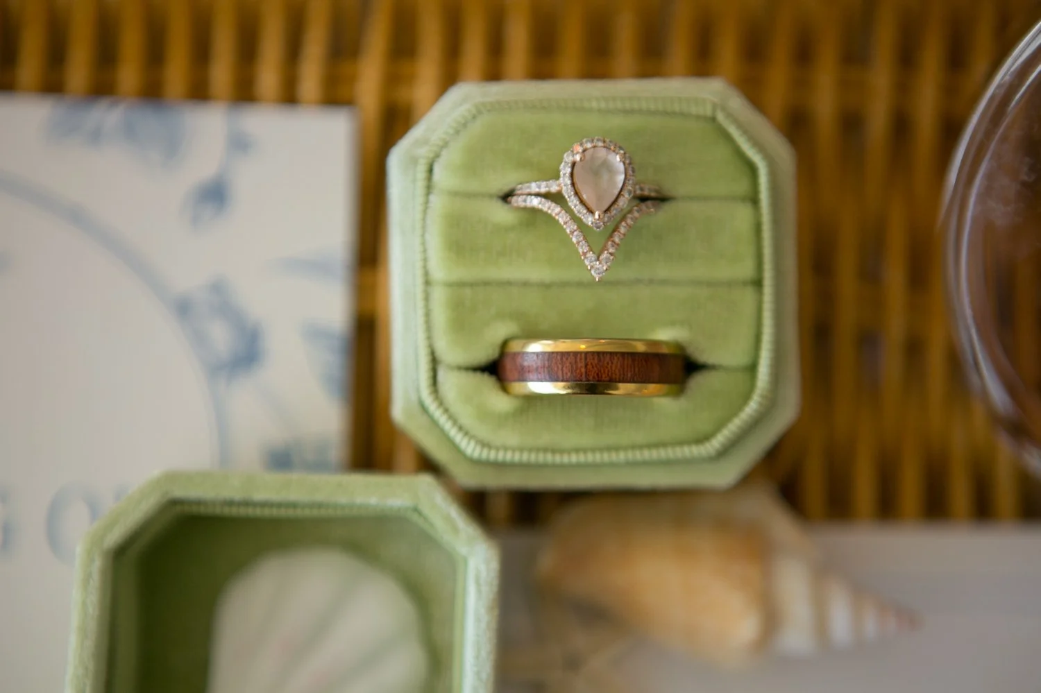 Pear diamond engagement ring with chevron halo band and wood inlay groom's wedding band in a sage green velvet ring box