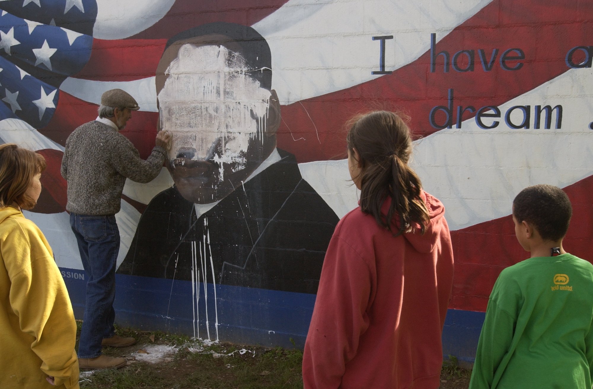  Children at the Martin Luther King Jr. Memorial Center, from left, Carisa Folck, 10, Letticia Perea, 10, and L.T. Fisher, 6, watch as Pat Mahoney works to remove white paint from the MLK mural Wednesday. The act of vandalism is being investigated as