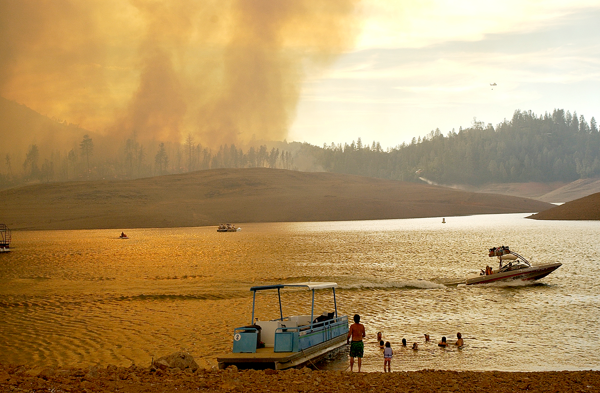  Shasta Lake boaters watch as the Bear Fire burns near the reservoir Wednesday. Officials said the fire was moving north toward the lake, unlike the October 1999 blaze that was driven by south winds and destroyed 174 homes 