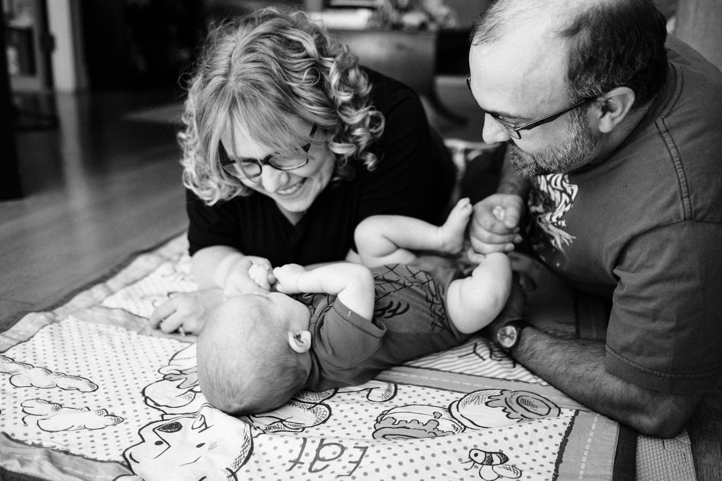 Mother and father playing with baby on blanket