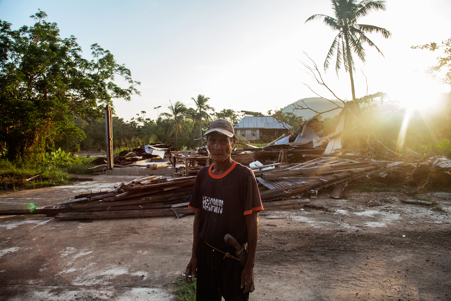  An Indigenous migrant from Culion living on Busuanga Island in Northern Palawan stands in front of a building leveled by Typhoon Haiyan in 2013.&nbsp; 