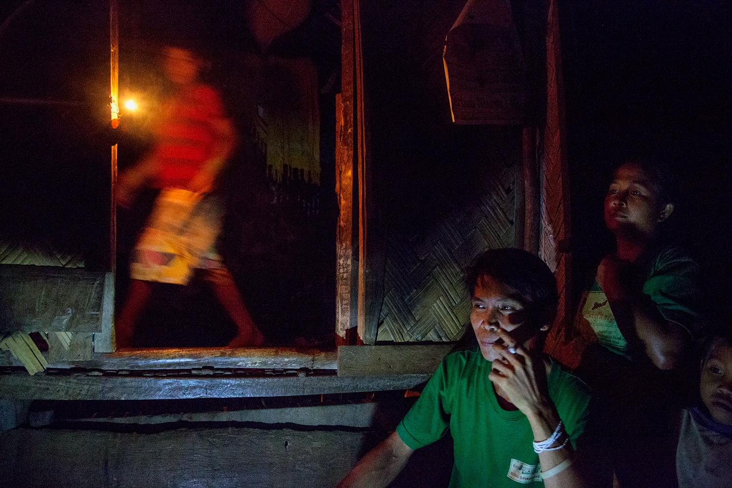  A family in the Tula-Tula community sit together in the light of a battery powered lamp and oil lamp outside their family home. In 2011 they were fighting against mining explorations in the area. Currently their area is safe but the issue of mining 