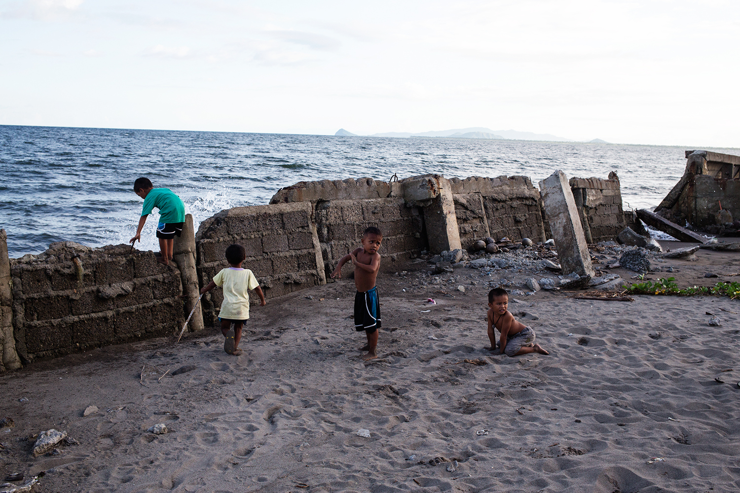  Children play by the water, on a wall torn apart by Typhoon Haiyan in the tent city near San Jose airport, Tacloban Leyte. 