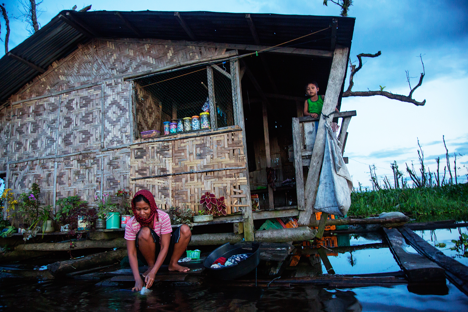  A woman from the Monobo community of Agusan Marsh washes the family dishes outside her home at sunset in the floating village.&nbsp;&nbsp; 