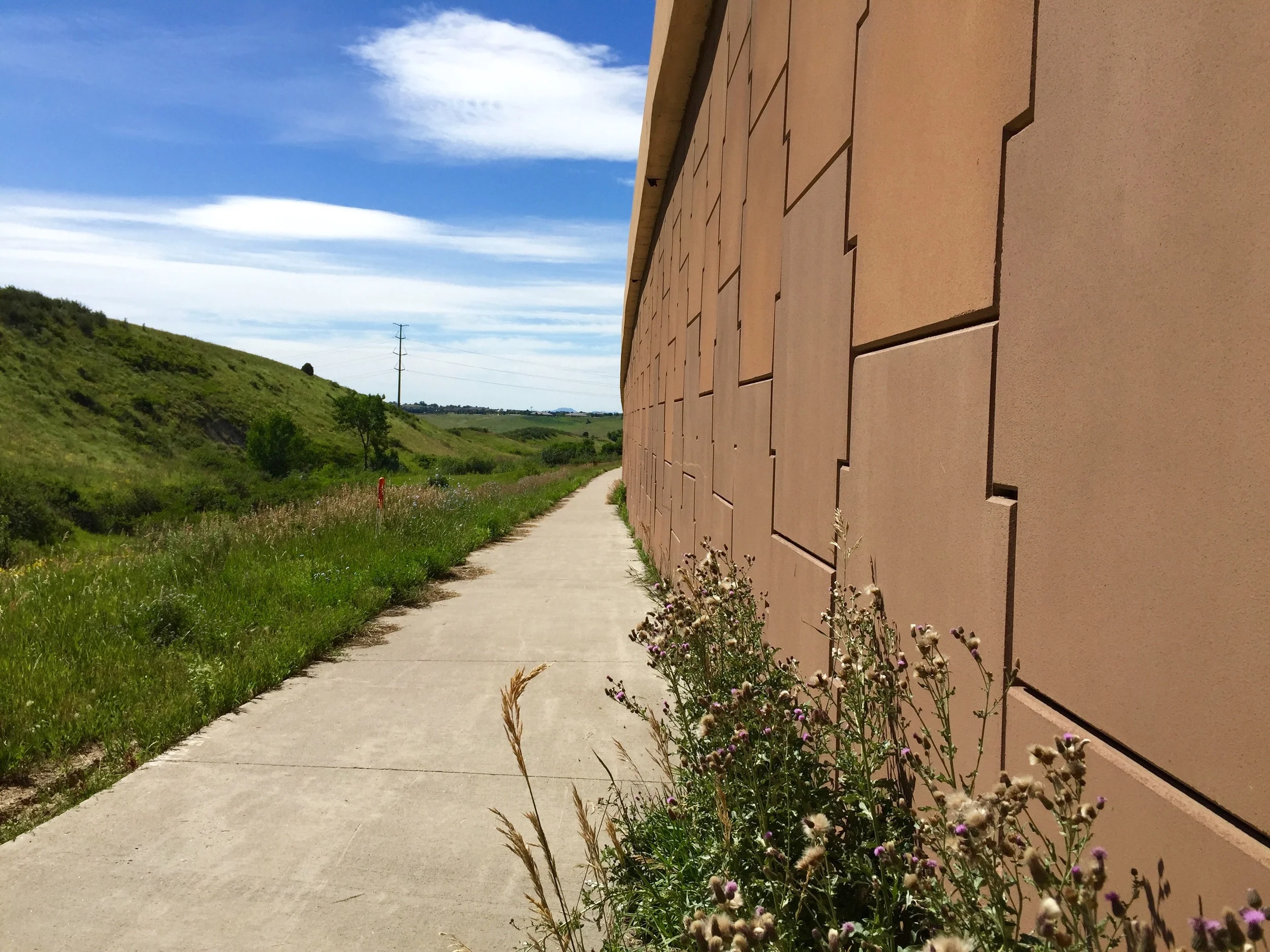 The urban and the wild each take a side of the trail along C-470
