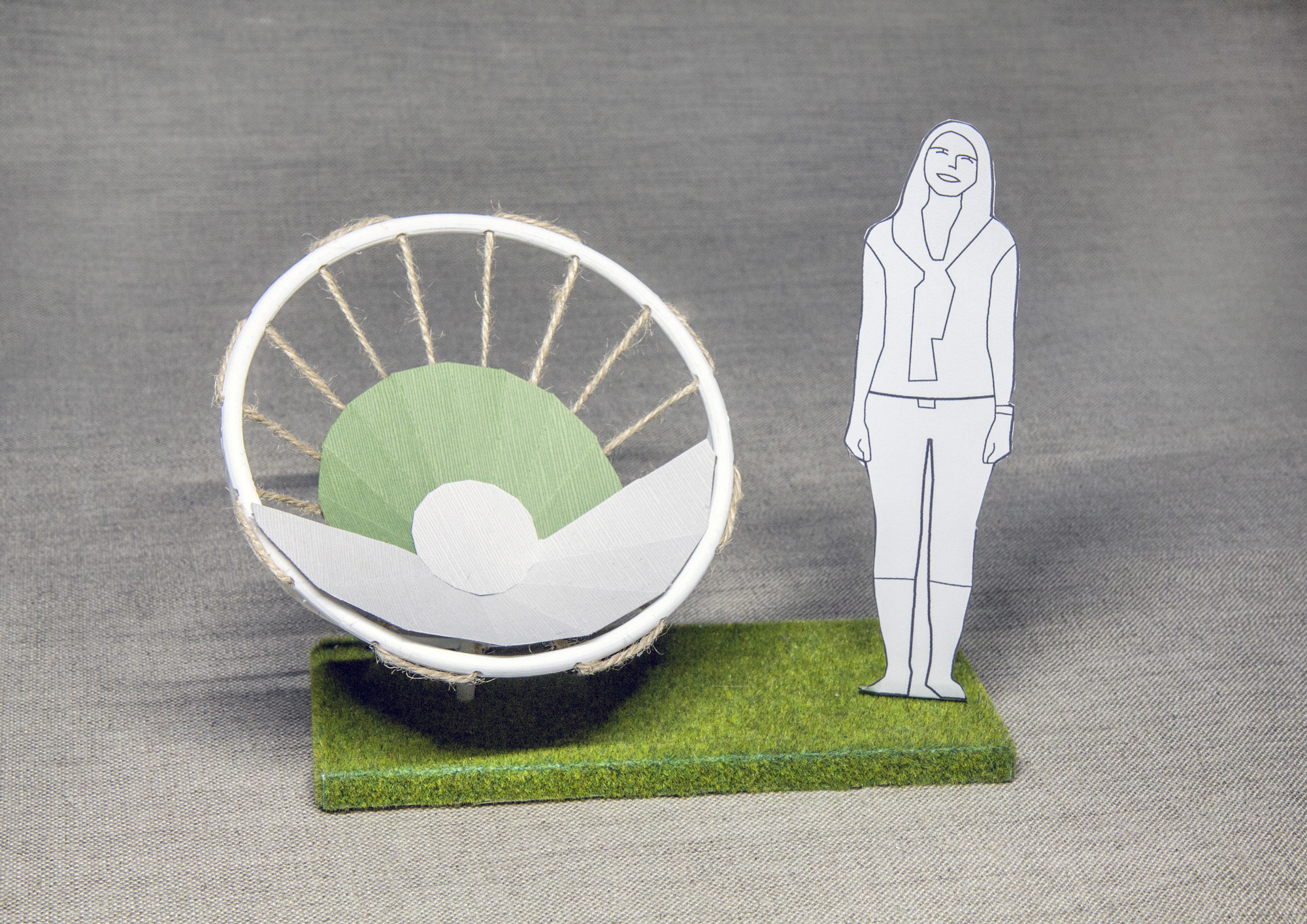 Allowing the chair to swivel on its center axis, in combination with considered spacing, allows the chair to function as a communal seating arrangement or a solitary one. The arching circular beam protects and embraces the seated person, and the powder coated seat panels move dynamically, thanks to the seat being suspended midair by playground ropes.