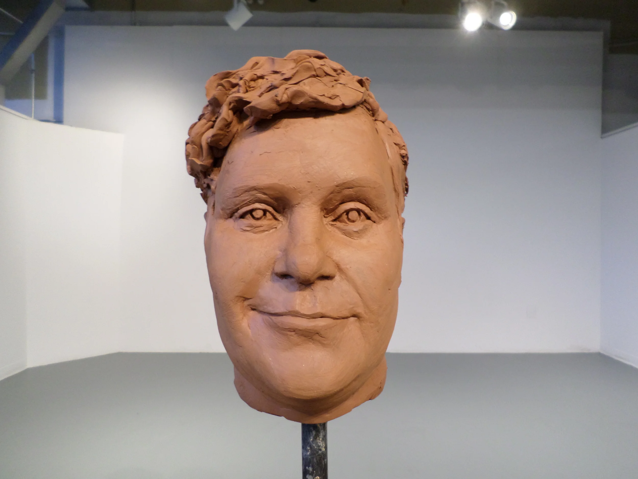 After sculpting the head and facial expression, I needed to hollow out the head. Inside, I had an armature consisting of a pipe, toilet float, expandable foam, and wire. I cut the top of the head off with a wire, avoiding the ears and face. Once hollowed out, I punched plenty of holes into the clay to allow moisture to escape more easily from the clay when it is fired. Thanks to my friend and inspirational artist Roberto Lugo, it is being fired! Hopefully it doesn't explode... Once I joined the two head pieces back together with clay slip (I scored the edges of the clay first), I finished off Brooks' fabulous hair texture, added his very identifiable glasses, and placed wax on the thin parts to keep them from drying out too fast and cracking. The wax is the white stuff that you can see on the glasses. 