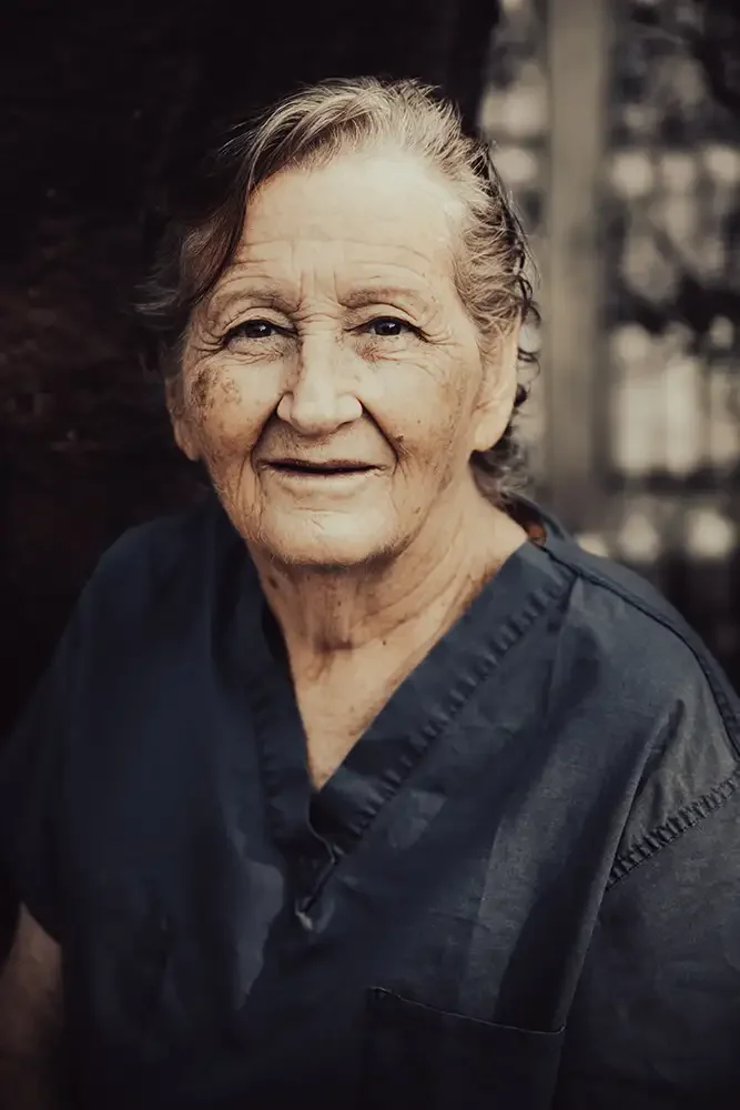A documentary portrait of Catherine Riley-Bryan, known as Momo Cat, sitting outdoors at the Bamboo School sanctuary near the Thailand-Myanmar border.
