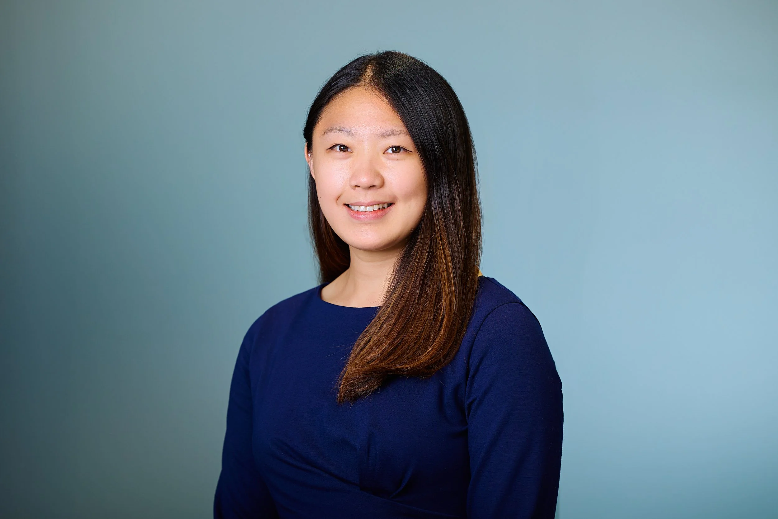 A modern corporate headshot of a female professional looking directly at the camera, demonstrating a relaxed and confident business style for London companies.