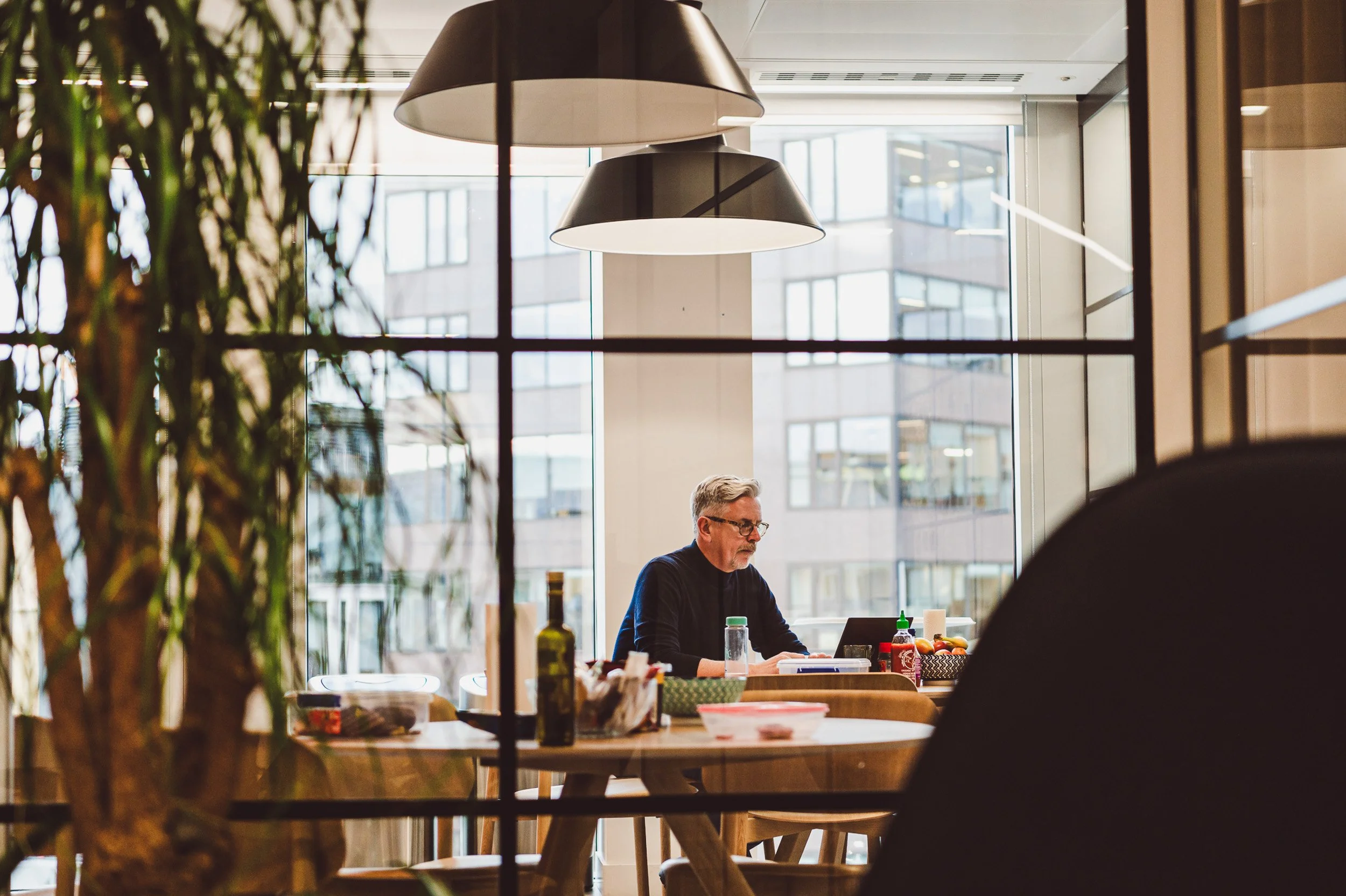 A candid, editorial-style portrait of a senior manager working in a glass-walled London office. The reflection of the city adds a cinematic, modern business feel. Shot by Scott Ramsey Photography and Videography.