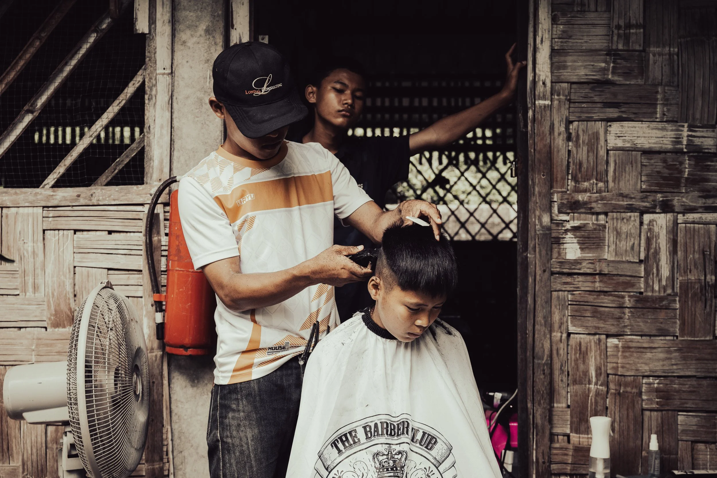 Documentary photo of a boy getting a haircut at The Bamboo School, Thailand-Myanmar border.