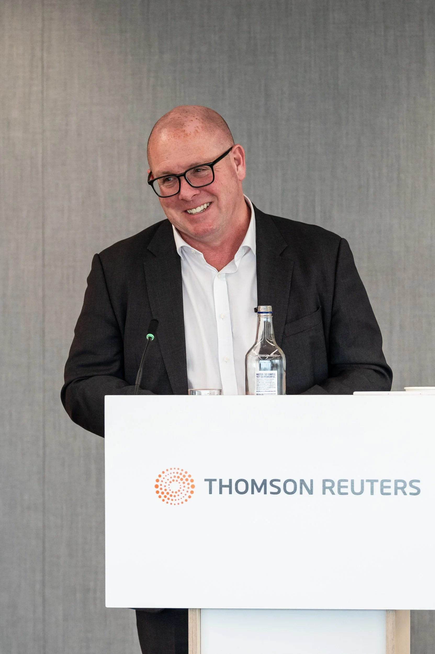Nick Leeson delivering a keynote speech at a branded Thomson Reuters podium in London. Professional PR and event photography by Scott Ramsey Photography & Videography, highlighting brand impact and high-profile speaker coverage.