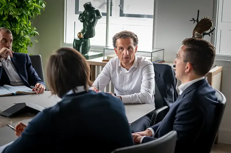 Senior executive in a white shirt leading a focused boardroom discussion with colleagues, demonstrating authentic corporate photography in London.