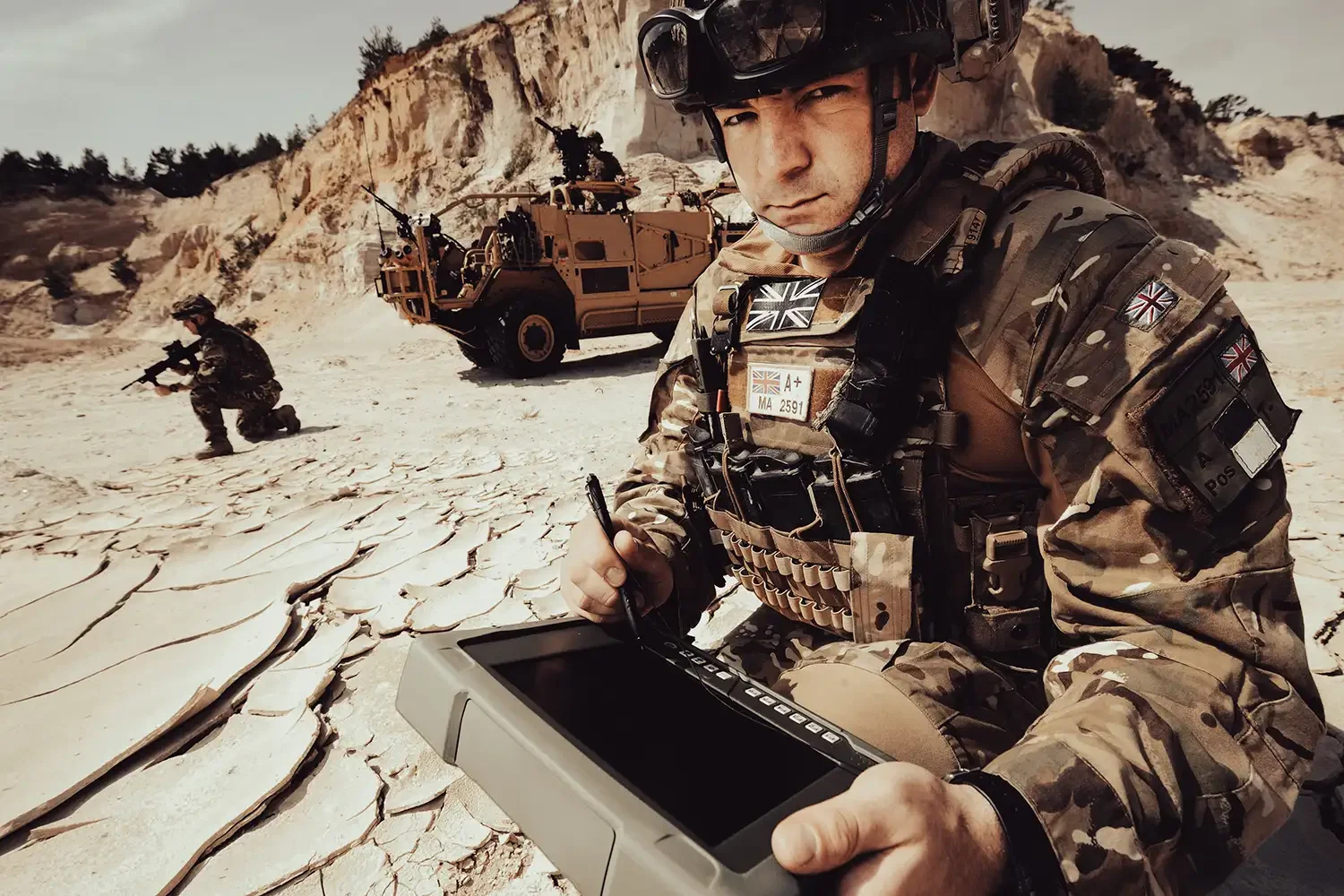 High-impact landscape commercial photography of a soldier with a military-grade tablet and armoured vehicle. Shot by London commercial photographer Scott Ramsey, specialising in high-stakes brand storytelling and location production.