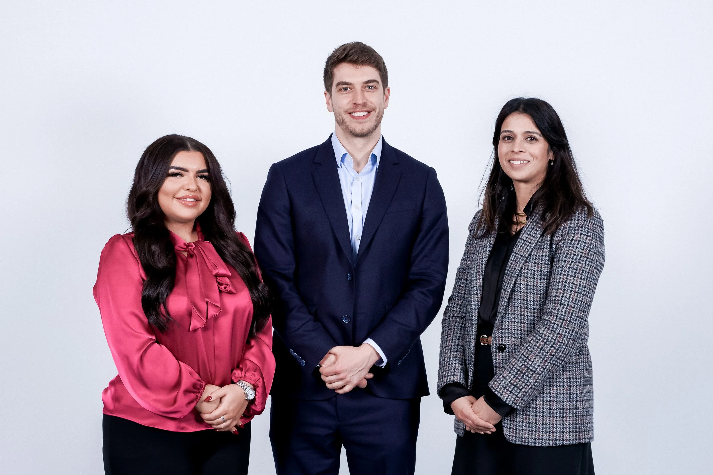 Close-up group portrait of three staff members on a white background. Demonstrating the clean, approachable lighting style used for Scott Ramsey's corporate team headshots.