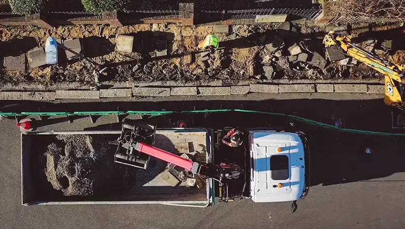 Professional overhead drone photography of an MBM Groundworks construction site in London, documenting crane logistics and pavement infrastructure for a high-scale industrial project.
