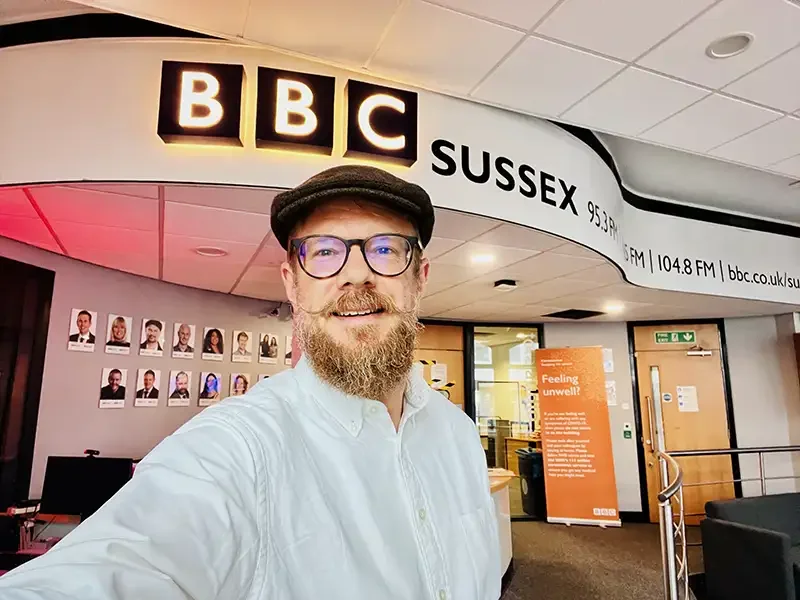 Scott Ramsey at the BBC Sussex radio studios. This image anchors his reputation as a trusted, recurring broadcaster and media guest for the BBC, where he discusses global humanitarian narratives and creative community initiatives.