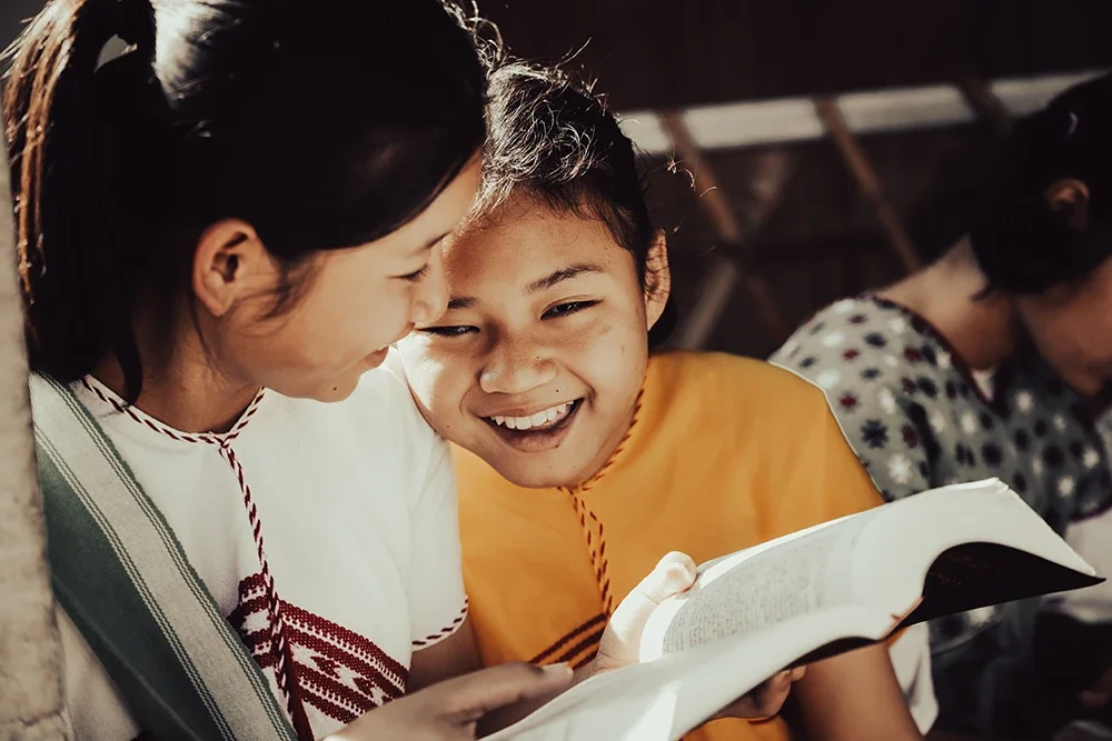 A young blind girl shares a moment of laughter with a friend at the Bamboo School near the Myanmar border. Scott Ramsey captures the resilient spirit and total inclusion found within this humanitarian sanctuary.