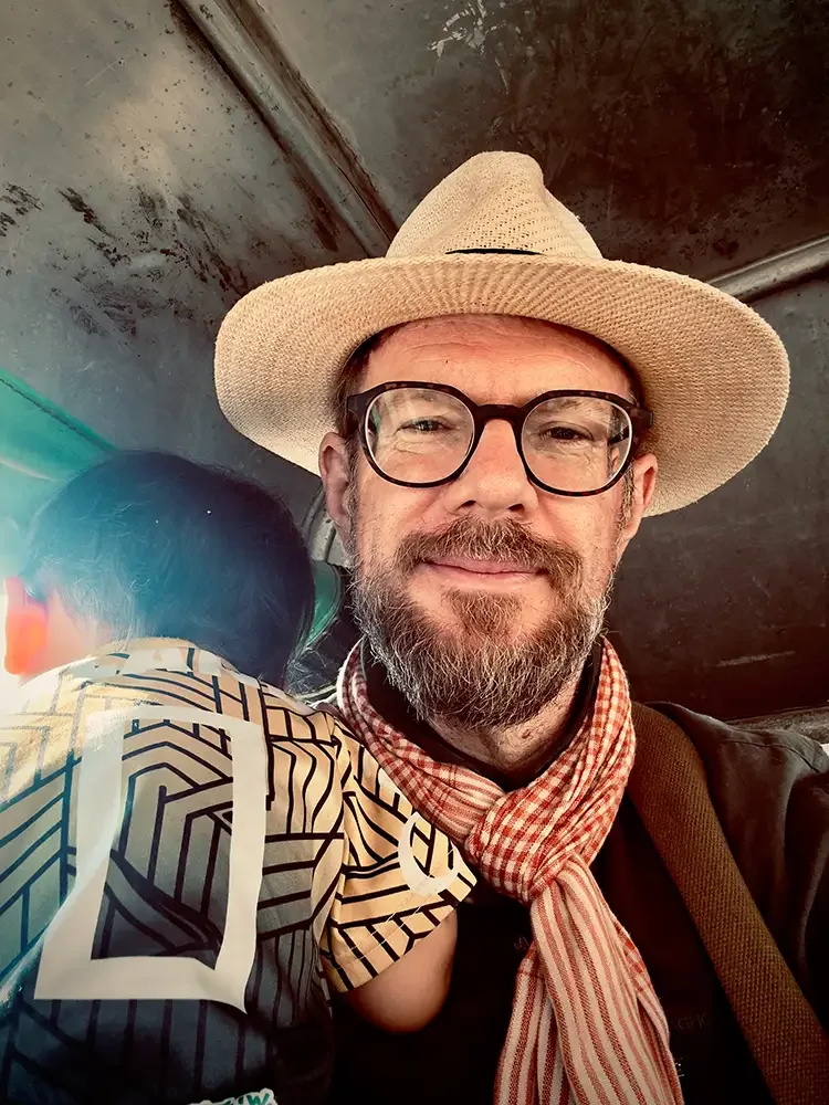 Scott Ramsey capturing humanitarian stories in Thailand, sitting with refugee children on a school bus to document their journey.