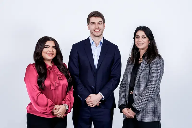 Close-up group portrait of three staff members on a white background. Demonstrating the clean, approachable lighting style used for Scott Ramsey's corporate team headshots.