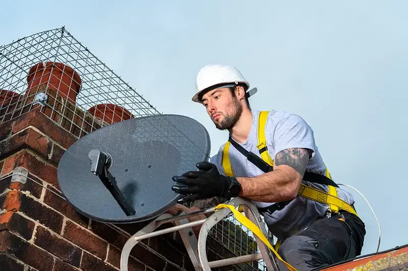 A professional commercial photograph of a technical engineer installing satellite equipment on a roof, demonstrating Scott Ramsey's ability to capture high-end industrial and technical assets on location.