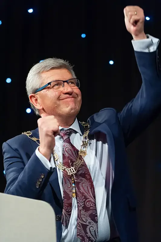 A vertical shot of an award winner celebrating on stage with a 'thumbs up' gesture at a London gala dinner. High-energy corporate event photography by Scott Ramsey Photography & Videography, capturing authentic moments of success.