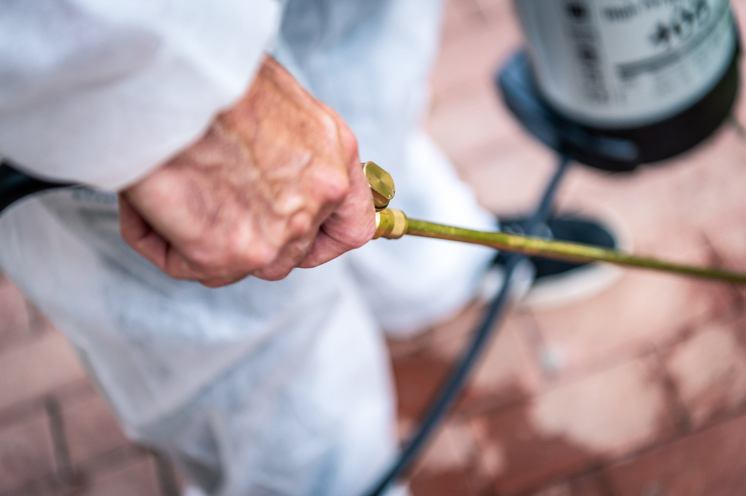 Close-up commercial photography of a Checkatrade pest controller using a spray wand. Shot by London agency Scott Ramsey.