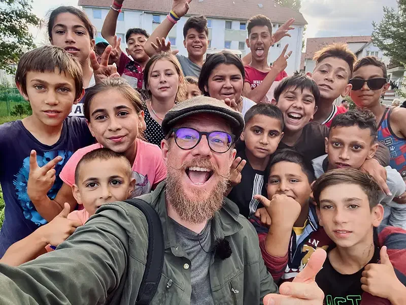 Documentary photographer Scott Ramsey sharing a moment of joy with local children while on a humanitarian assignment in Romania, illustrating the agency's commitment to telling untold stories.