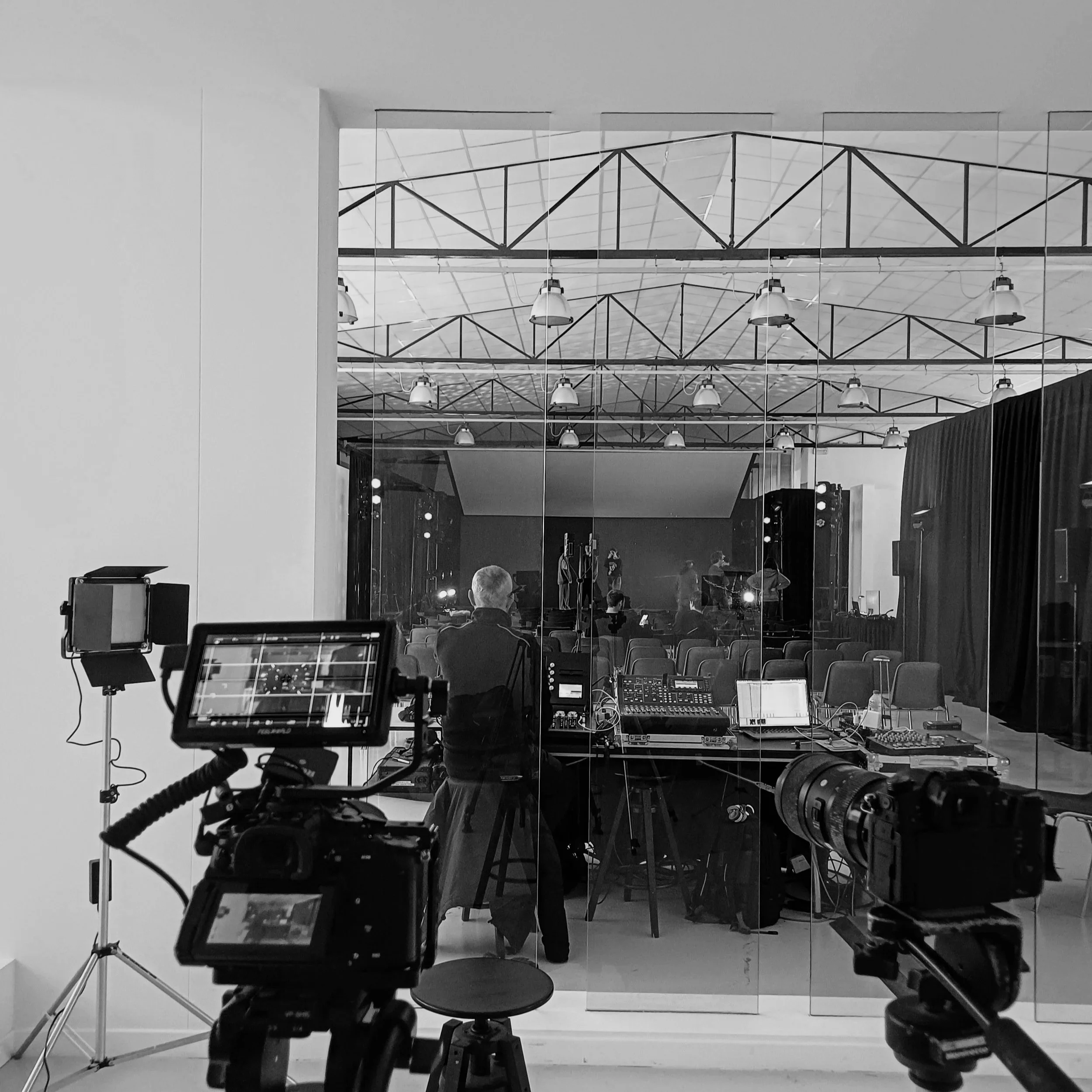 Set Alberto Romanotto Videomaker. Produzione documentario ABAV Verona Interno di una sala di registrazione audio con strumentazione digitale, computer e mixer. Sullo sfondo, persone e attrezzature in un ambiente per produzione audio.