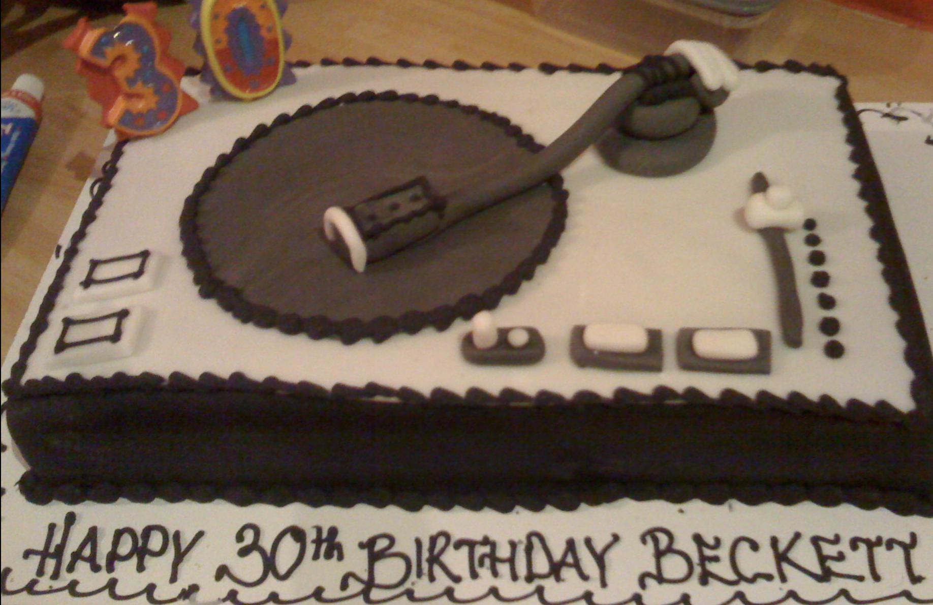 A birthday cake celebrating a 30th birthday for Beckett, decorated with a hockey theme. The cake is rectangular with black and white icing, featuring a hockey stick and puck, and the number '30' on top. Text on the cake reads 'HAPPY 30TH BIRTHDAY BEC