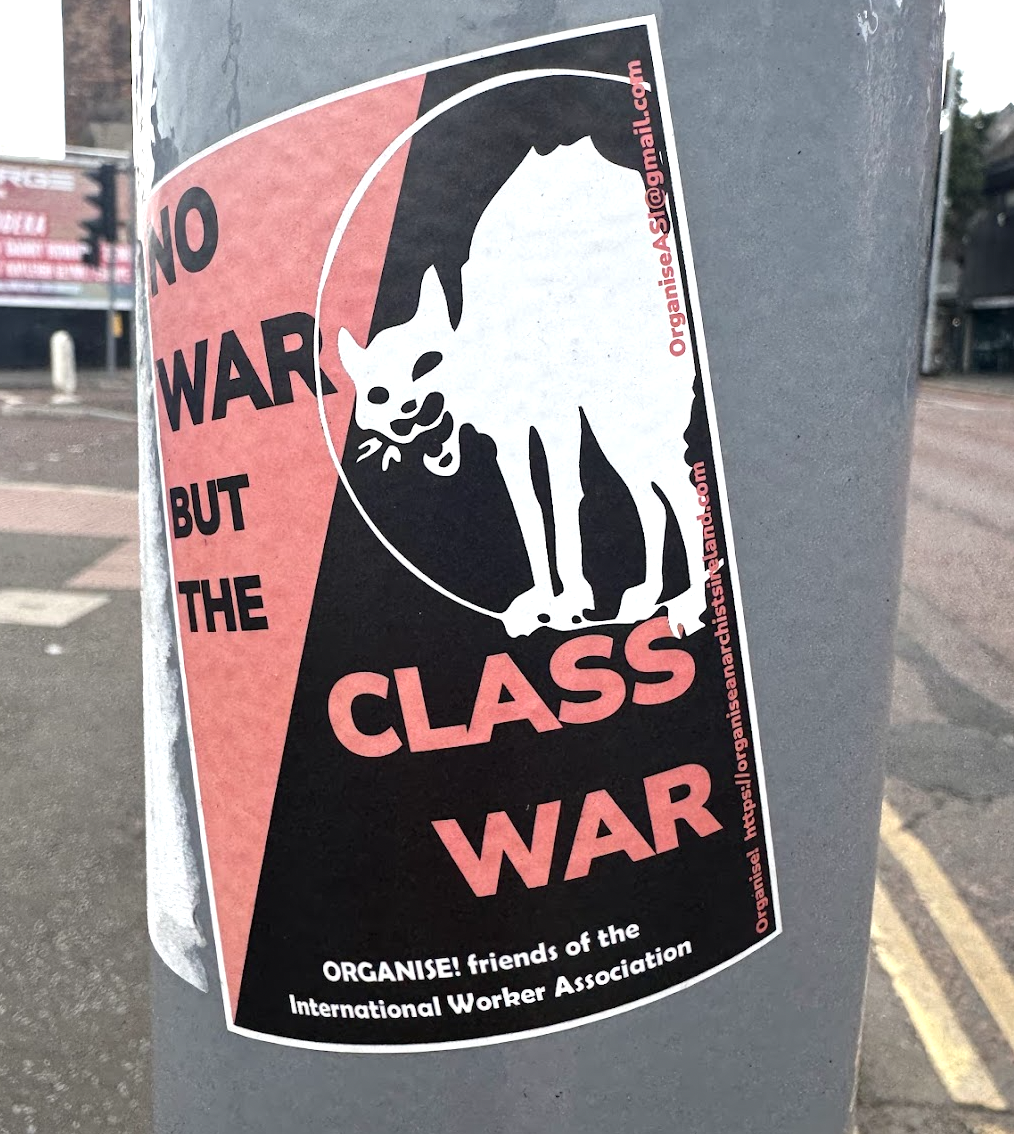 Sticker on a pole with a protest message showing a rat with a broken tail. The text says: 'No War But the Class War'. It is from friends of the International Worker Association.