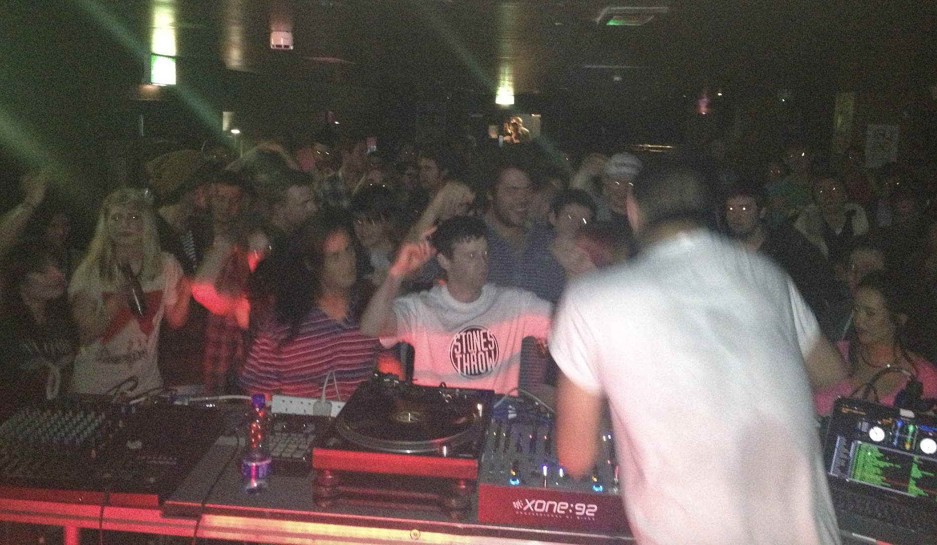 DJ performing at a crowded nightclub with many people dancing and enjoying the music.