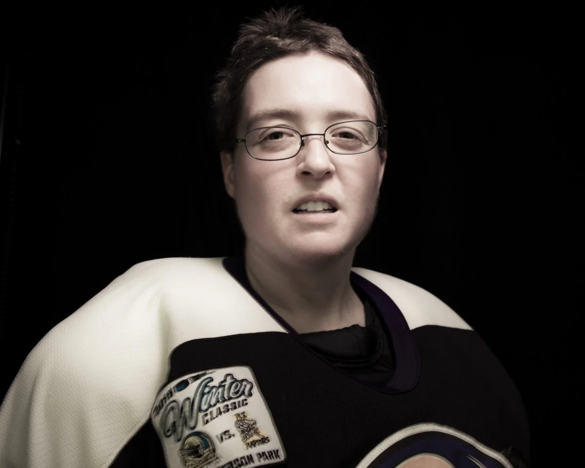 Close-up of a woman in a hockey jersey with a patch reading 'Wonton Classic' on her right shoulder, against a black background.