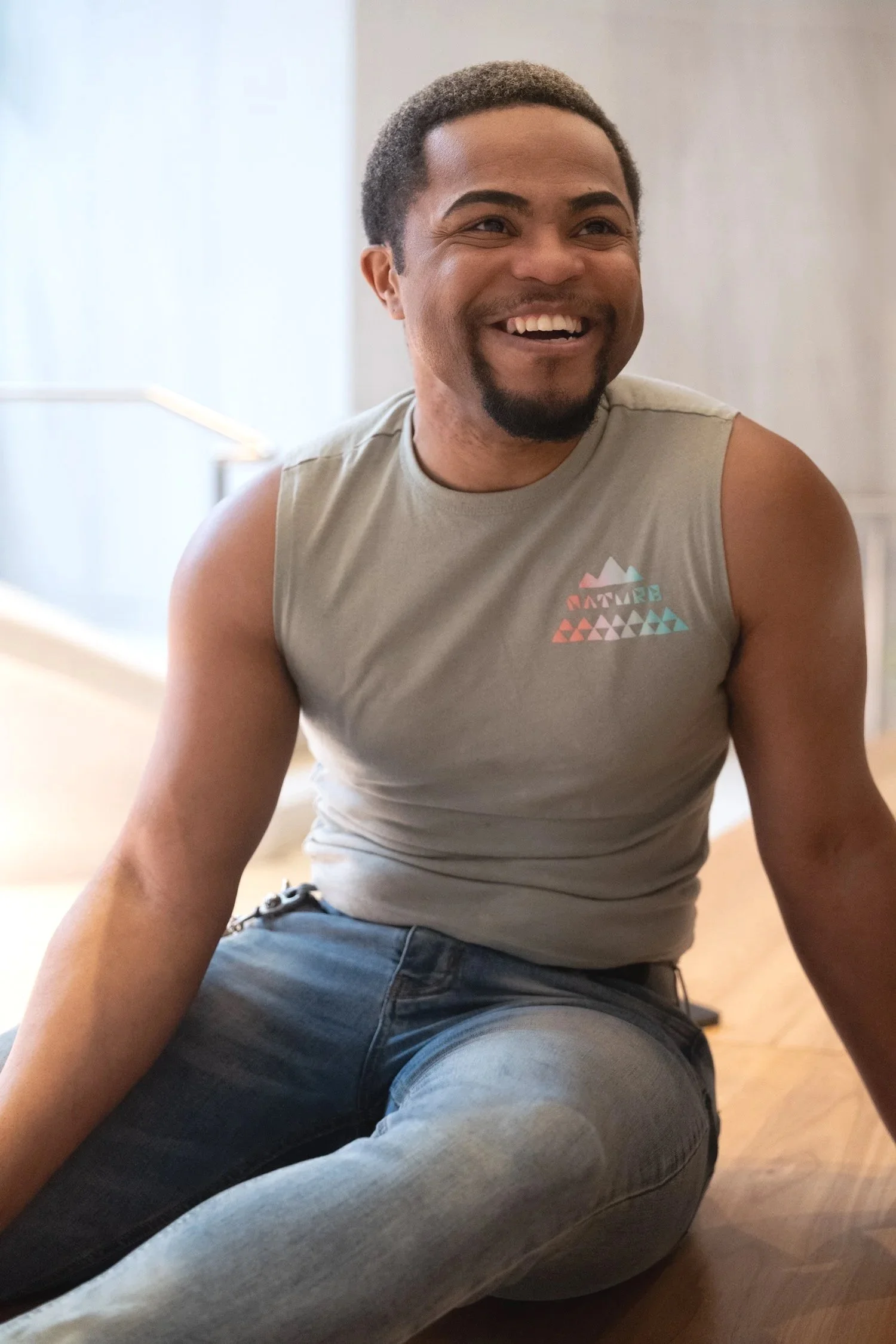 Young smiling man in a gray tank-top and jeans, photographed in natural light in Downtown Boston.