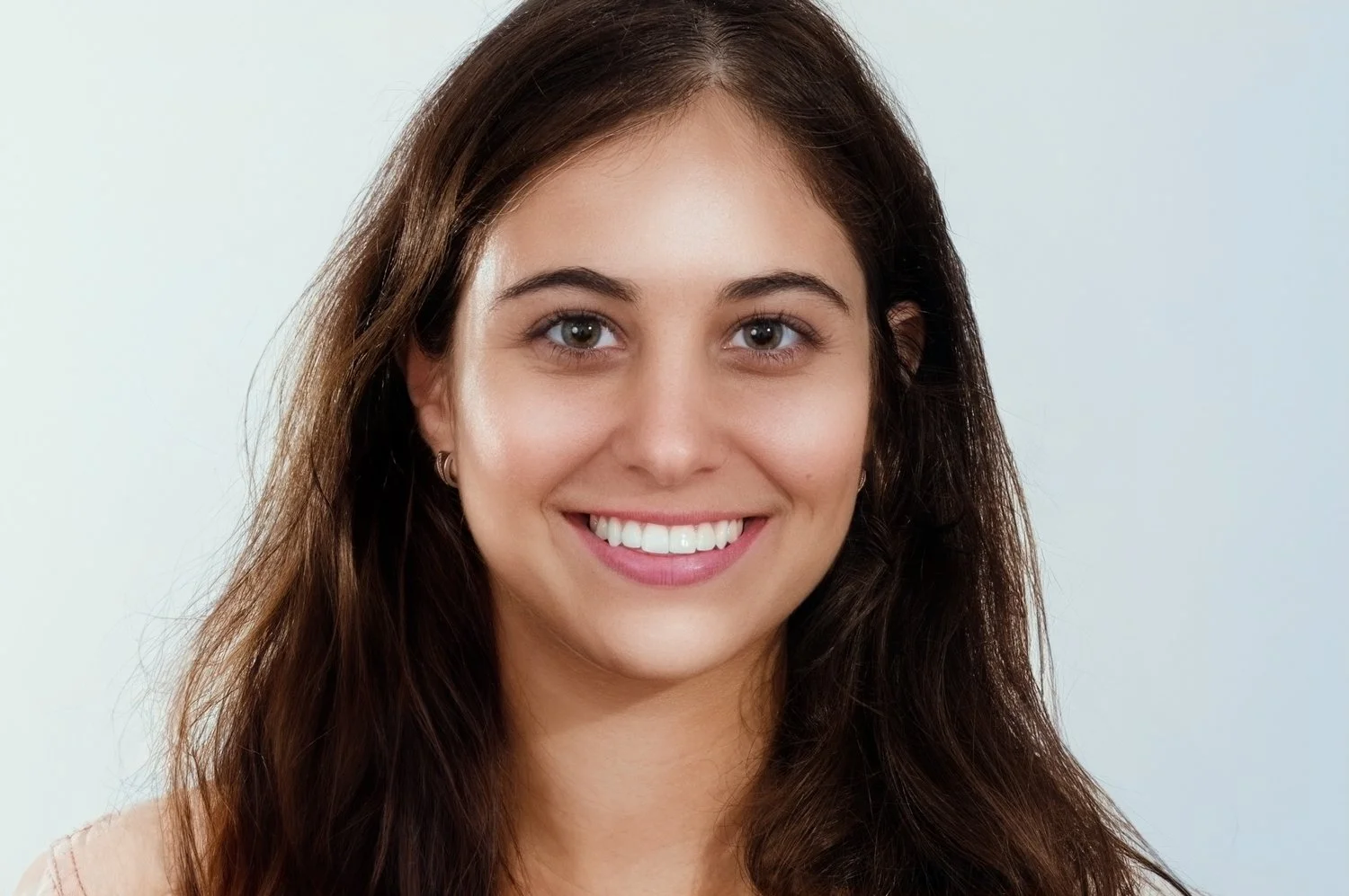 Headshot of a young, smiling woman with long brown hair, against a neutral background.