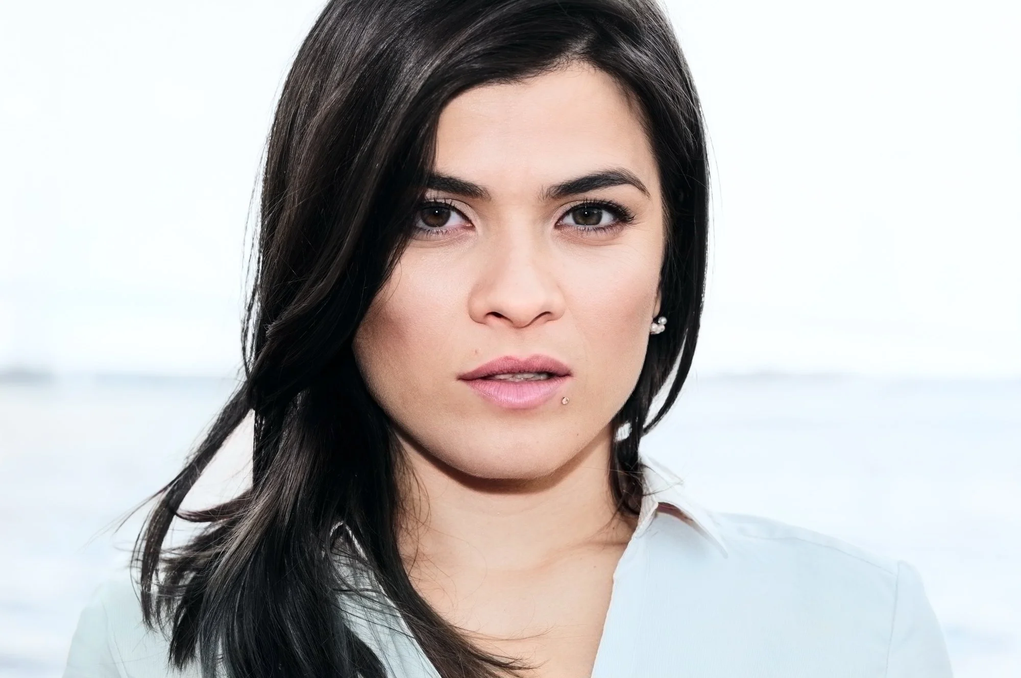 Portrait of a young woman with dark hair facing the camera in a candid, flash-lit outdoor shot.