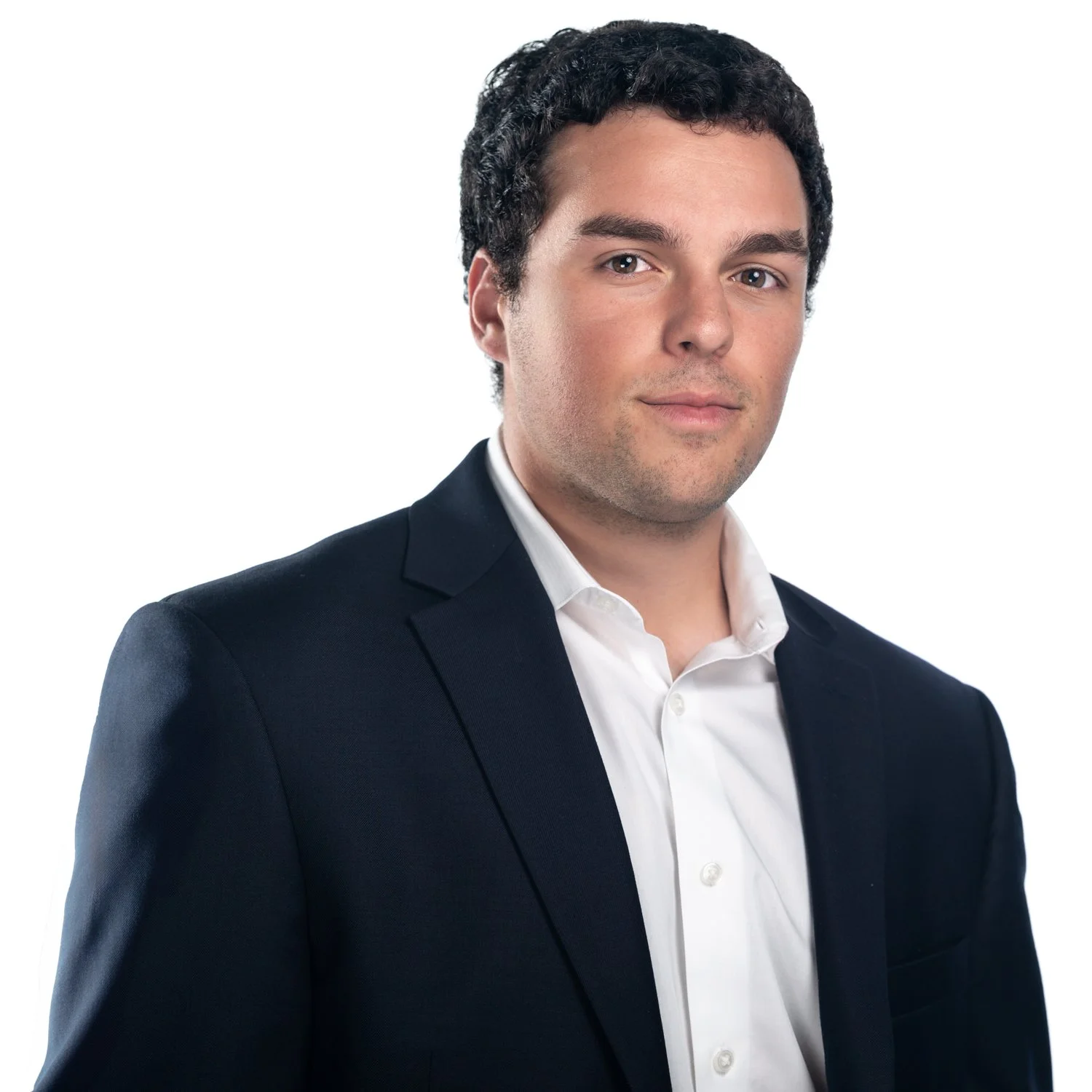 A man in a navy blue suit and white shirt posing against a plain white background.